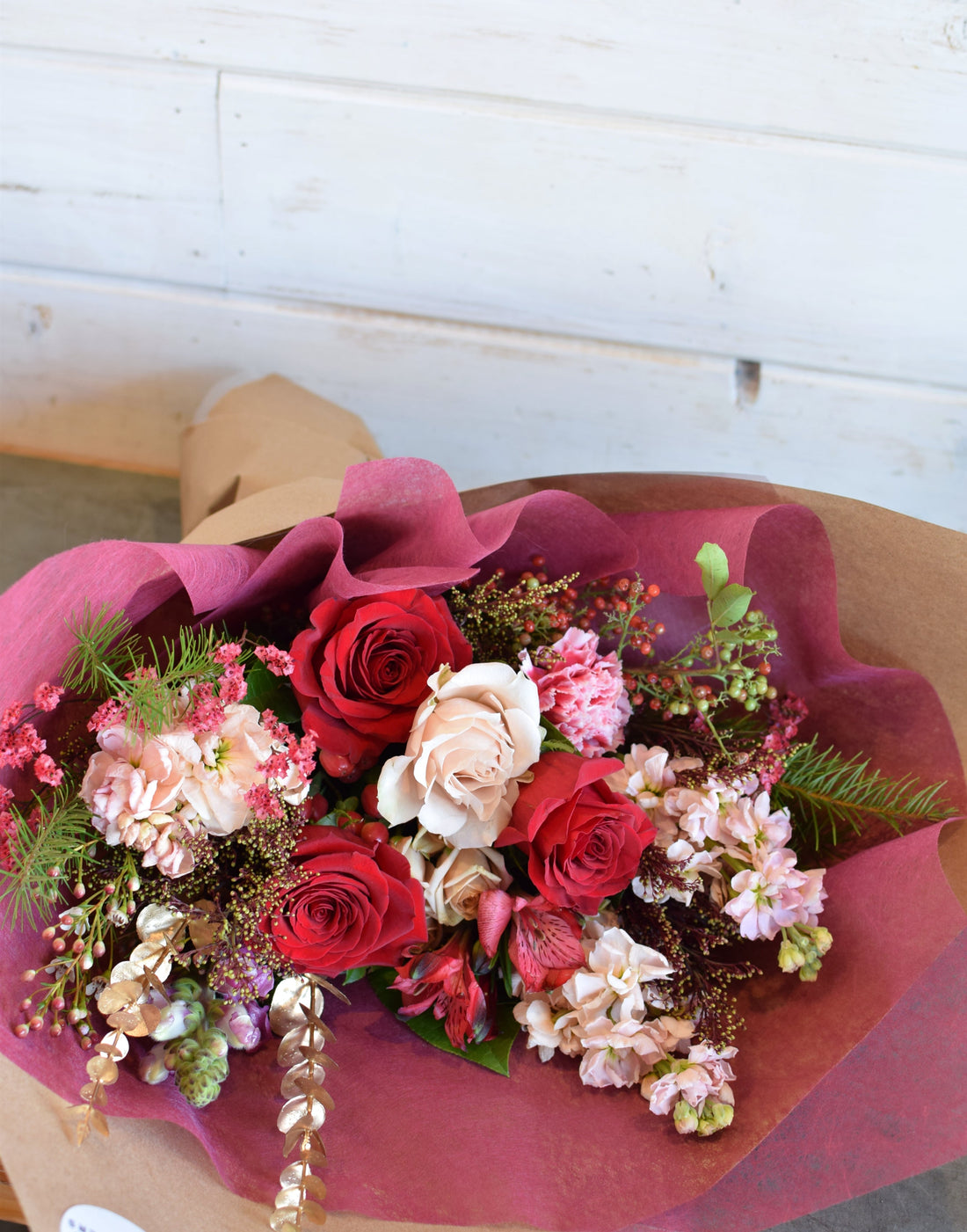 christmas holday flower bouquet with red roses and winter foliage and holiday fixings