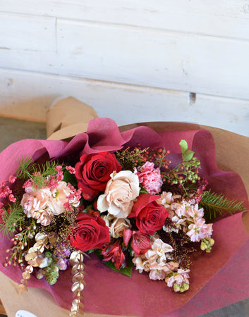 christmas holday flower bouquet with red roses and winter foliage and holiday fixings