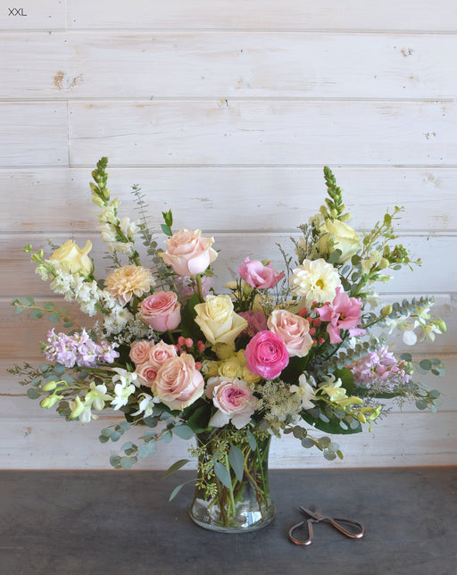 XXL Custom Vibe in pink and white, featuring seasonal blooms like roses, lilies, and stock, arranged in a chic glass vase.