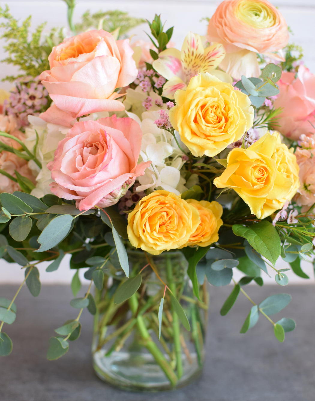 Front view of the round Creamsicle centerpiece showing its low profile short glass vase layout, ideal for table decor.
