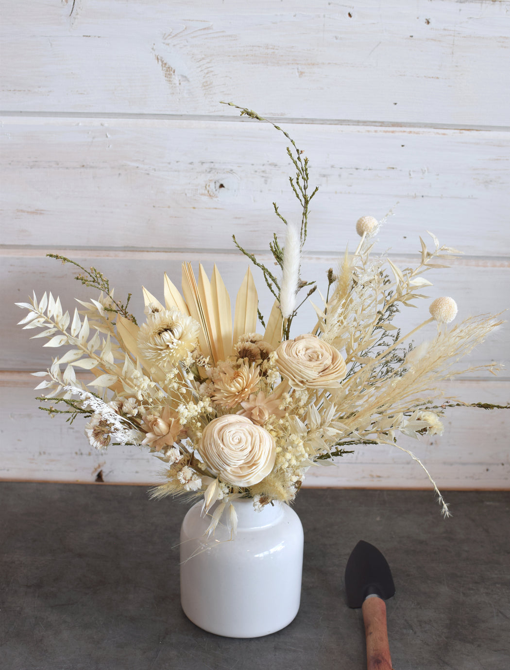 Everlasting ivory blooms arranged in a sleek, modern ceramic vase by Flowerful.