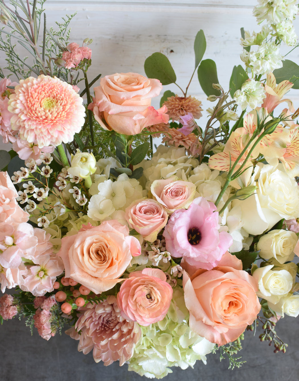 Bouquet of pink peach and white flowers with greenery.
