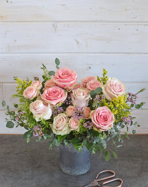 Pink Lemonade bouquet with pink roses, yellow solidago, eucalyptus, and seasonal fillers in a rustic galvanized vase.