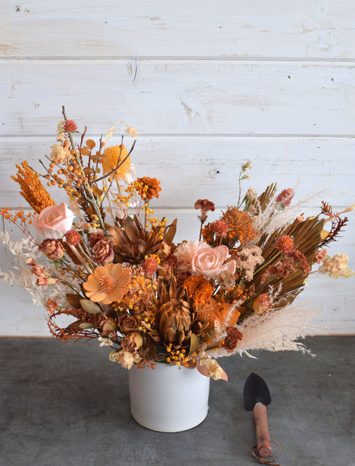 Dried flower arrangement in warm orange tones, displayed in a modern cement vase, perfect for adding lasting charm to any space, crafted by Flowerful in Laguna Woods, CA.